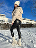 GlamShape™ Thermo Kunstlederleggings von Snodis gestylt mit hohen Stiefeln und einem Mantel für ein modisches Winteroutfit.